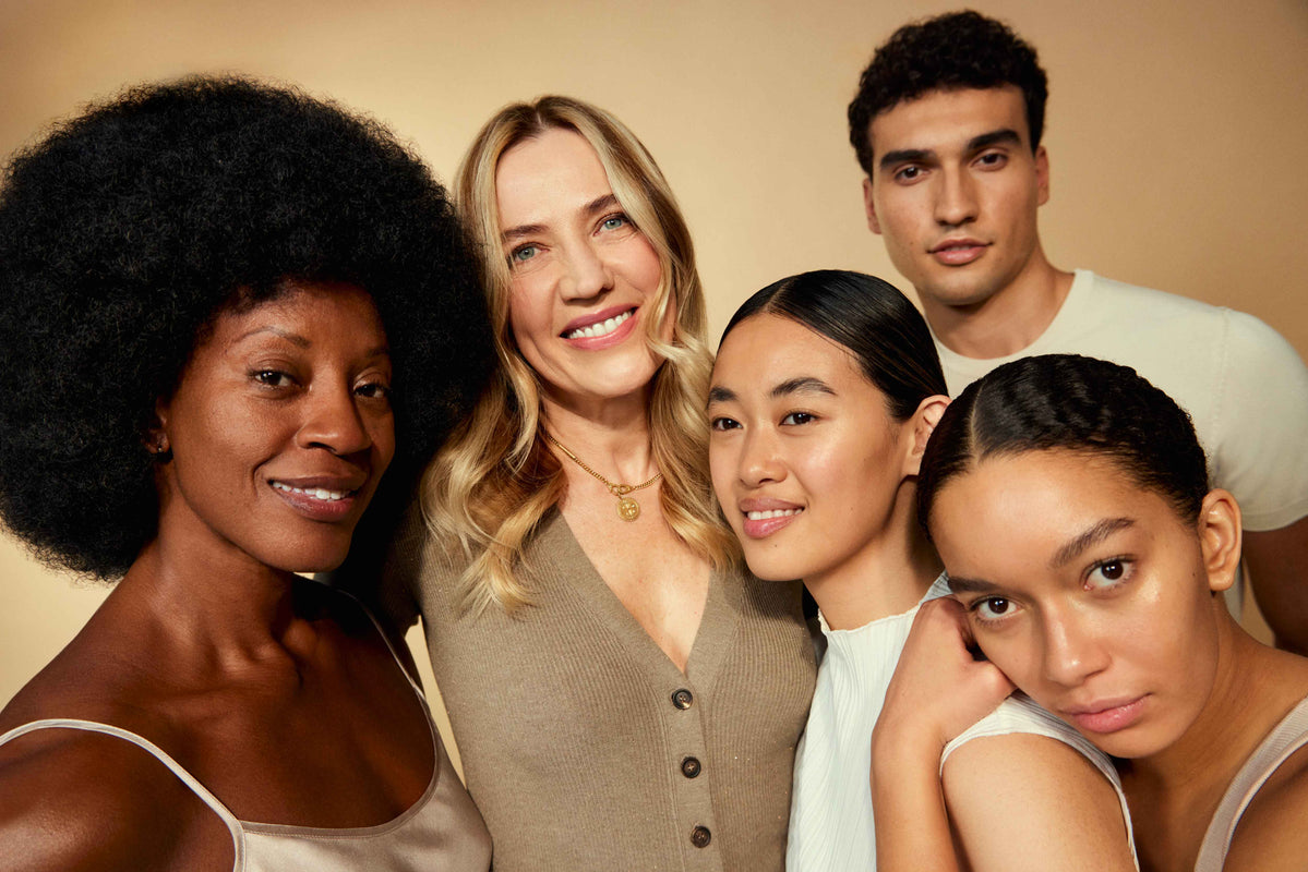 4 women and a man standing in front of a beige background.