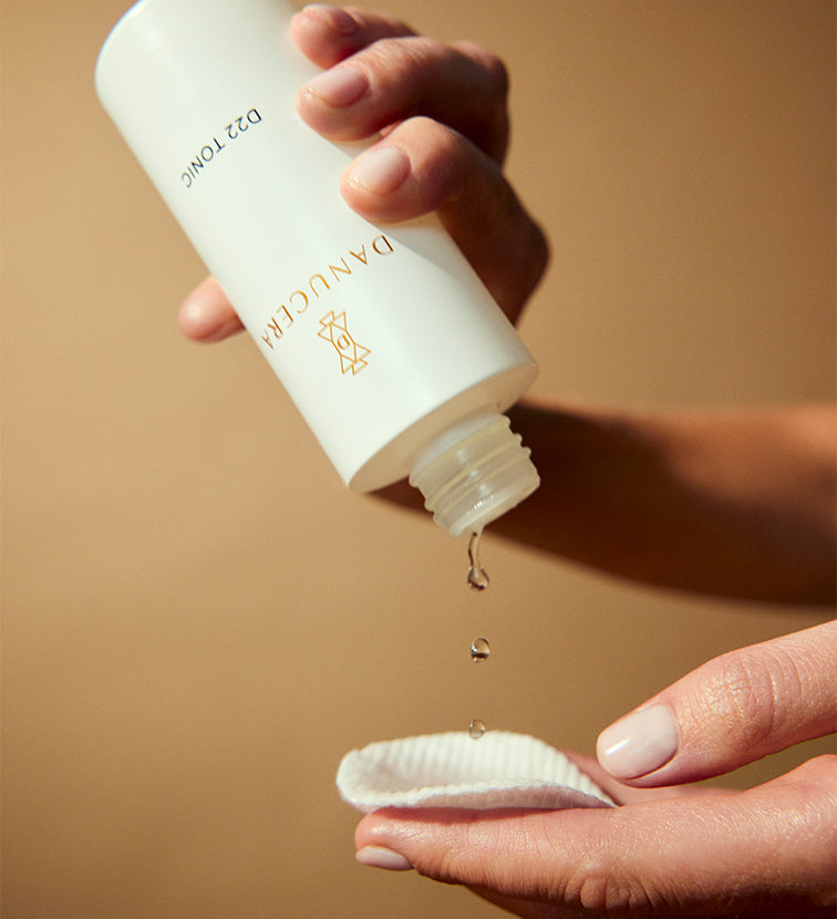 A person pouring out D22 Tonic water into a facial cleaning pad. 