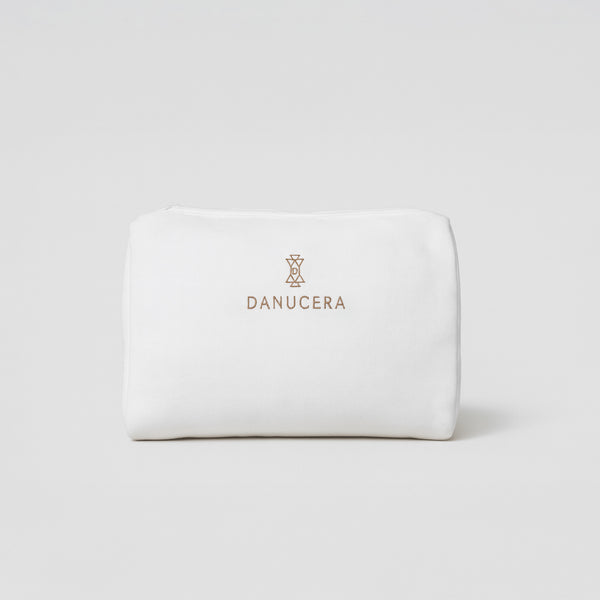 Danucera beauty bag in white with gold Danucera logo, pictured on a grey background. Perfect travel essential.